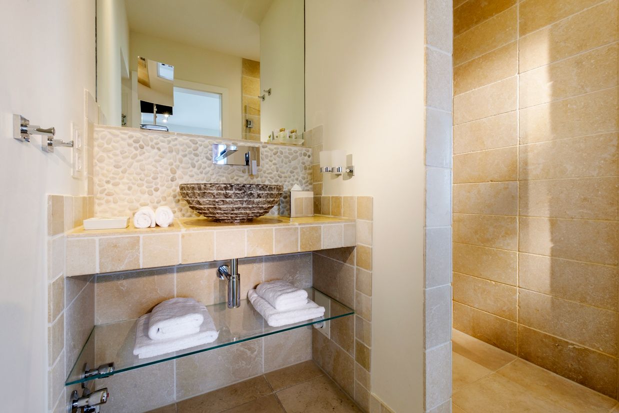 Badezimmer mit Waschtisch, ebenerdiger Regendusche und Spiegl im Hotel Strand
