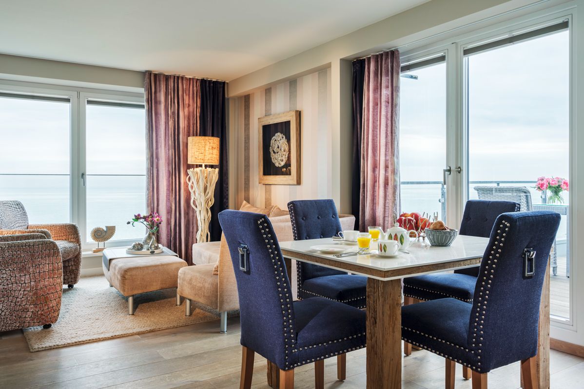 Ess- und Couchecke mit blauen Stühlen, Panoramfenster zum Balkon und Stehlampe